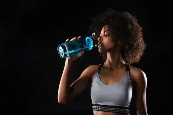 A woman promoting longevity by drinking water from a blue bottle.