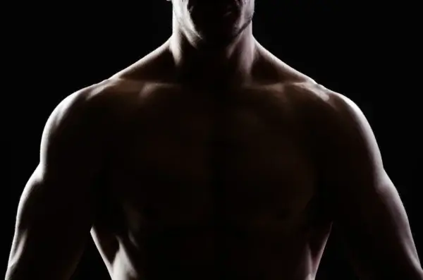 A silhouette of a muscular man on a dark background.