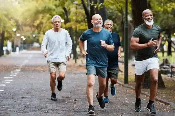 A group of elderly men promoting longevity by jogging in a park.