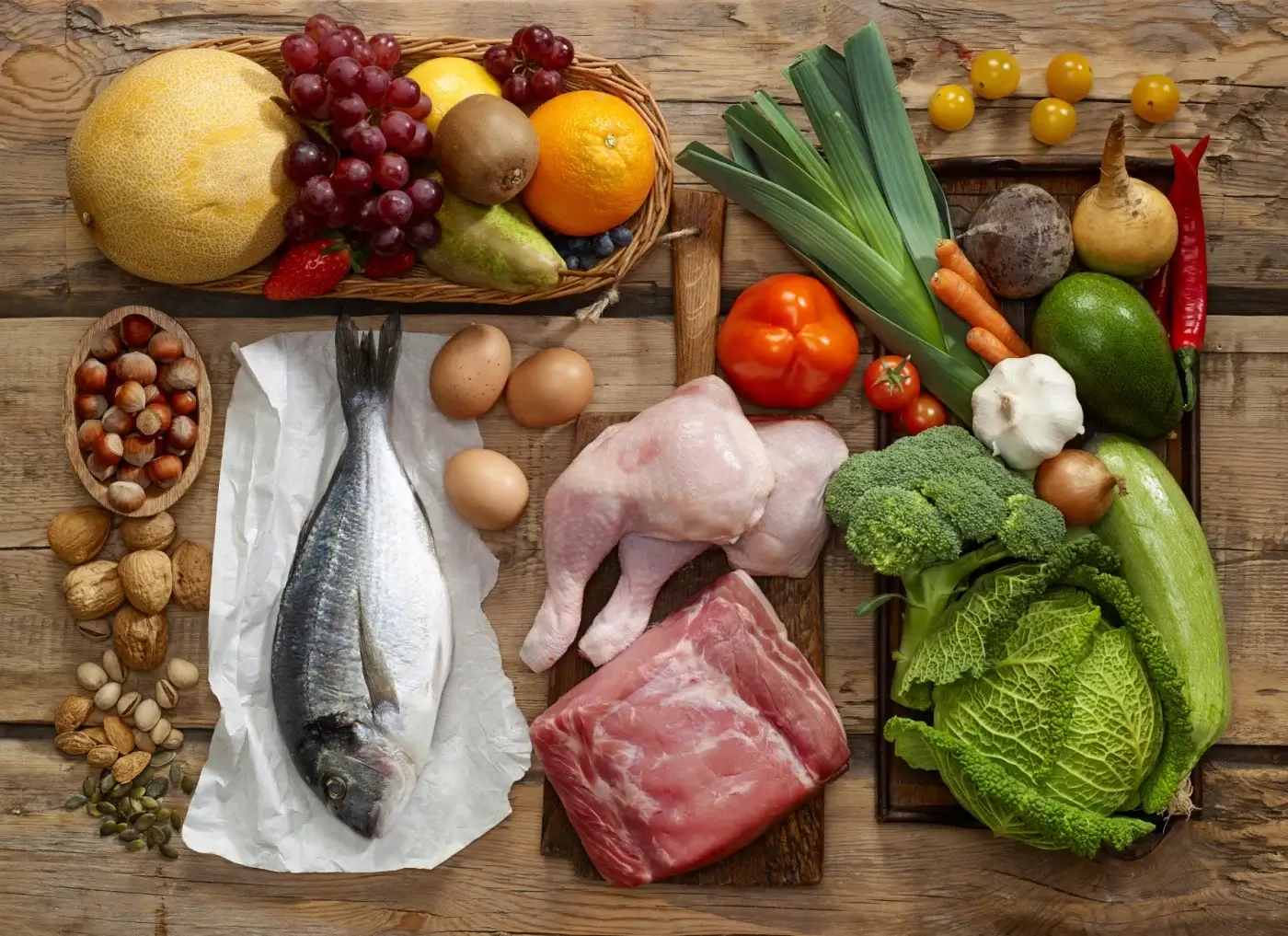 A variety of fruits and vegetables are laid out on a wooden table.