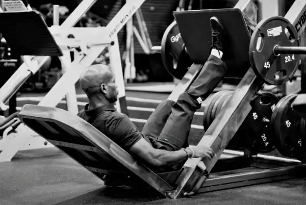 A person performs a single-leg press exercise on a leg press machine at the gym. The individual is seated and mastering the technique by pushing a weight-loaded platform with one leg at a time.