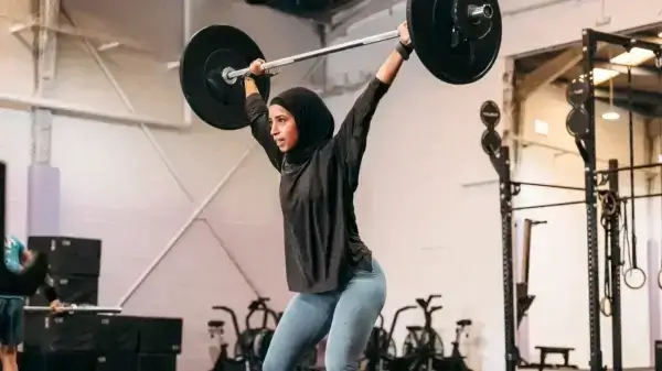 A woman focusing on longevity while lifting a barbell in a gym.