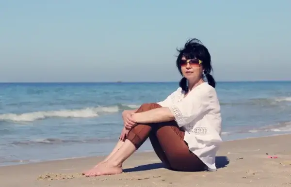 A woman enjoying the beach with sunglasses.